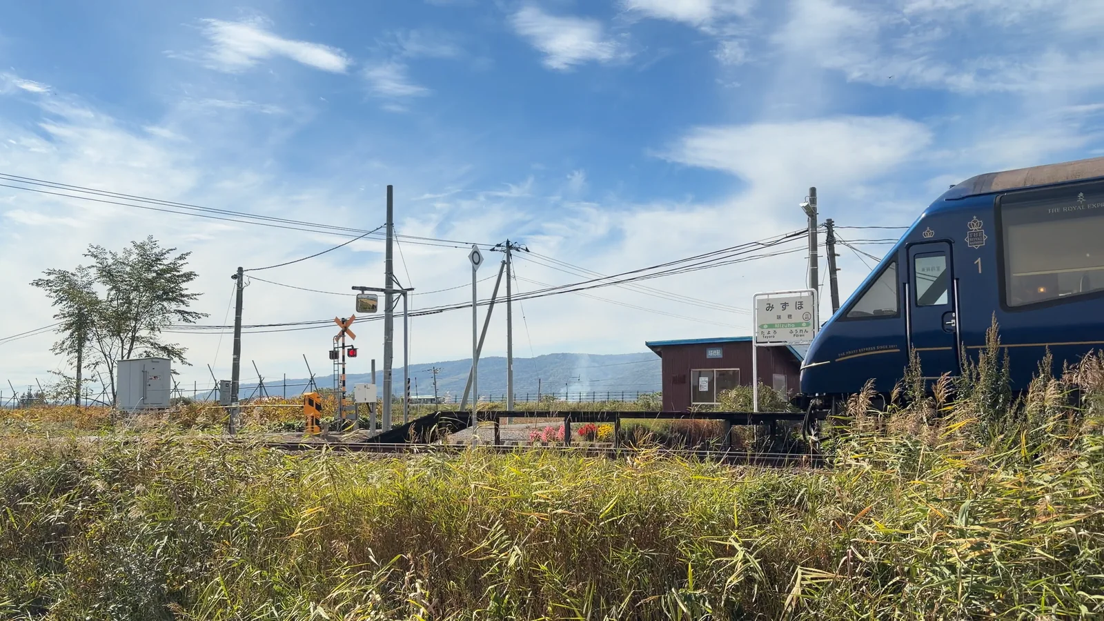瑞穂駅の待合室と駅名標の前を通過し北へ向かうTHE ROYAL EXPRESS
