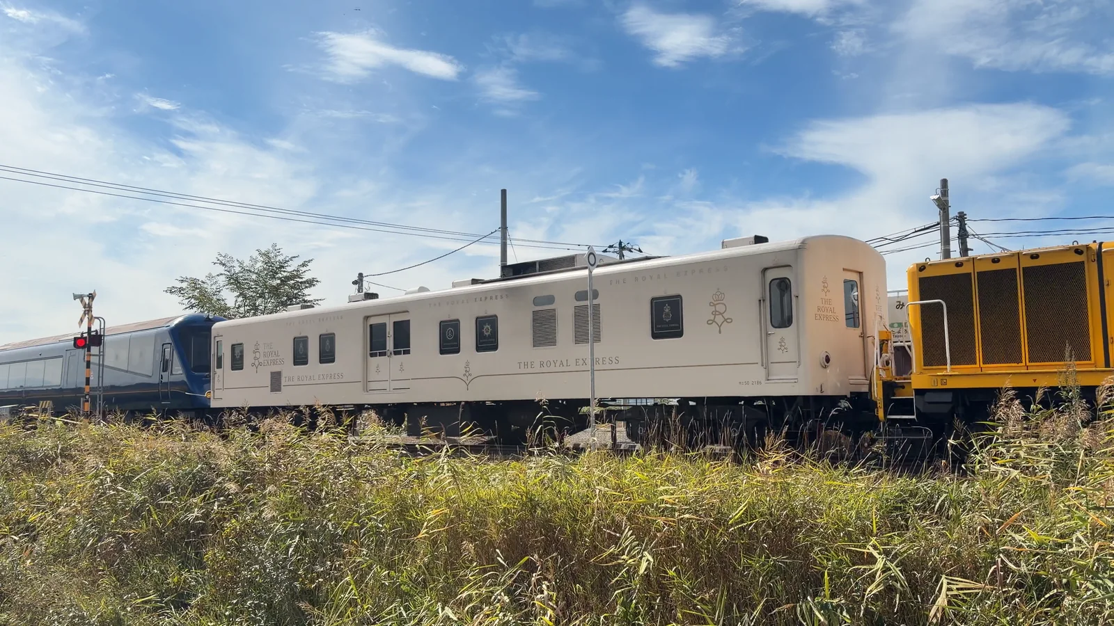 瑞穂駅を北へ通過するTHE ROYAL EXPRESSの白い車両と黄色い機関車