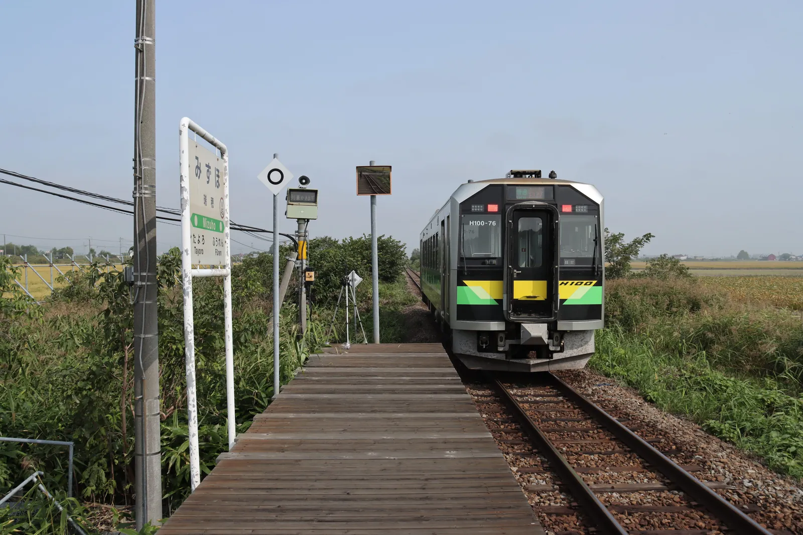 瑞穂駅の駅名標と木製ホーム、そのそばに停車する列車