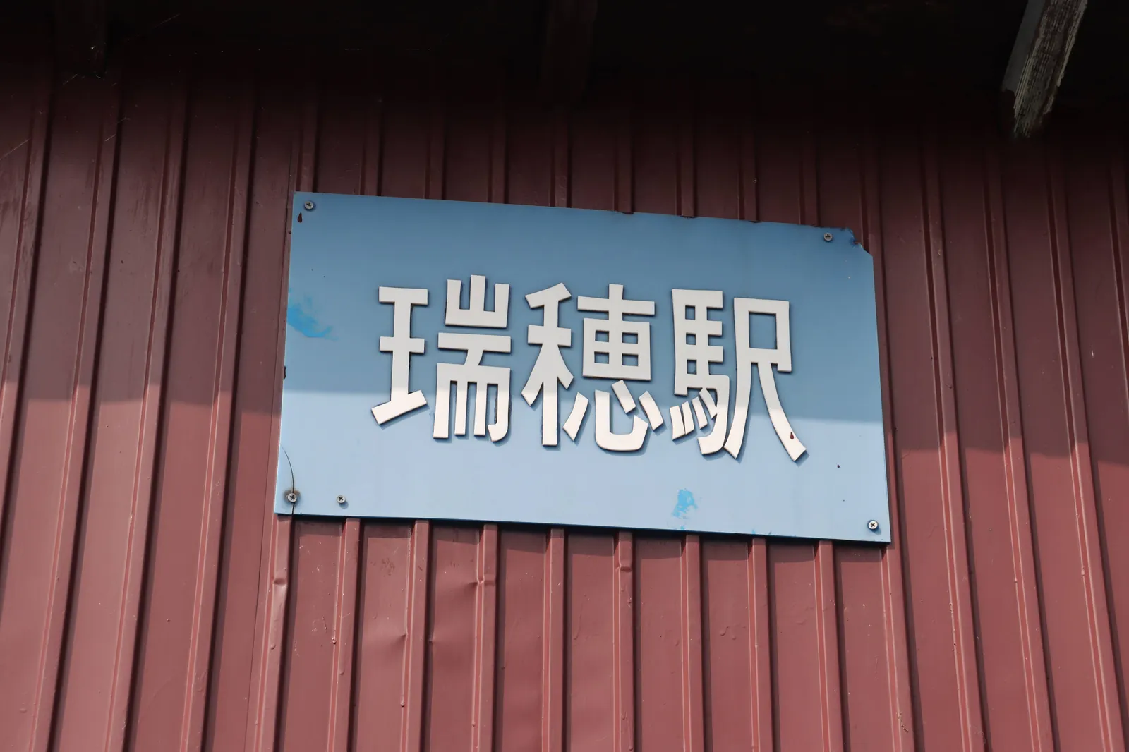 赤茶色の駅舎に掲げられた青い瑞穂駅の表示
