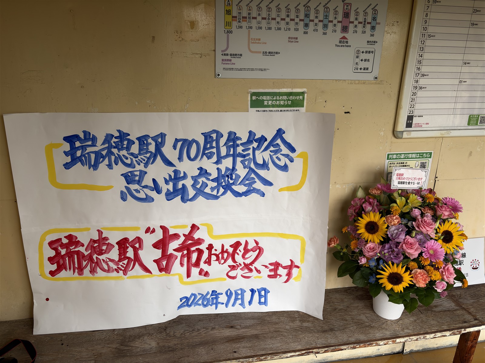 瑞穂駅の待合室に飾られた70周年記念の手書き看板と祝いの花